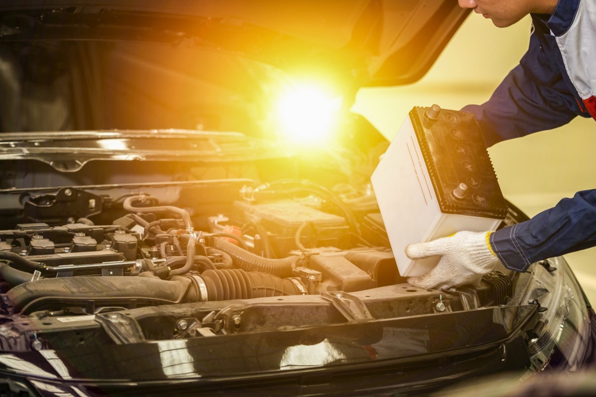 man taking battery out of car