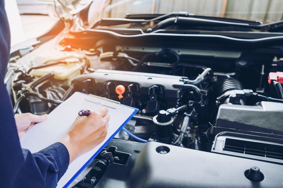 mechanic checking under hood of car