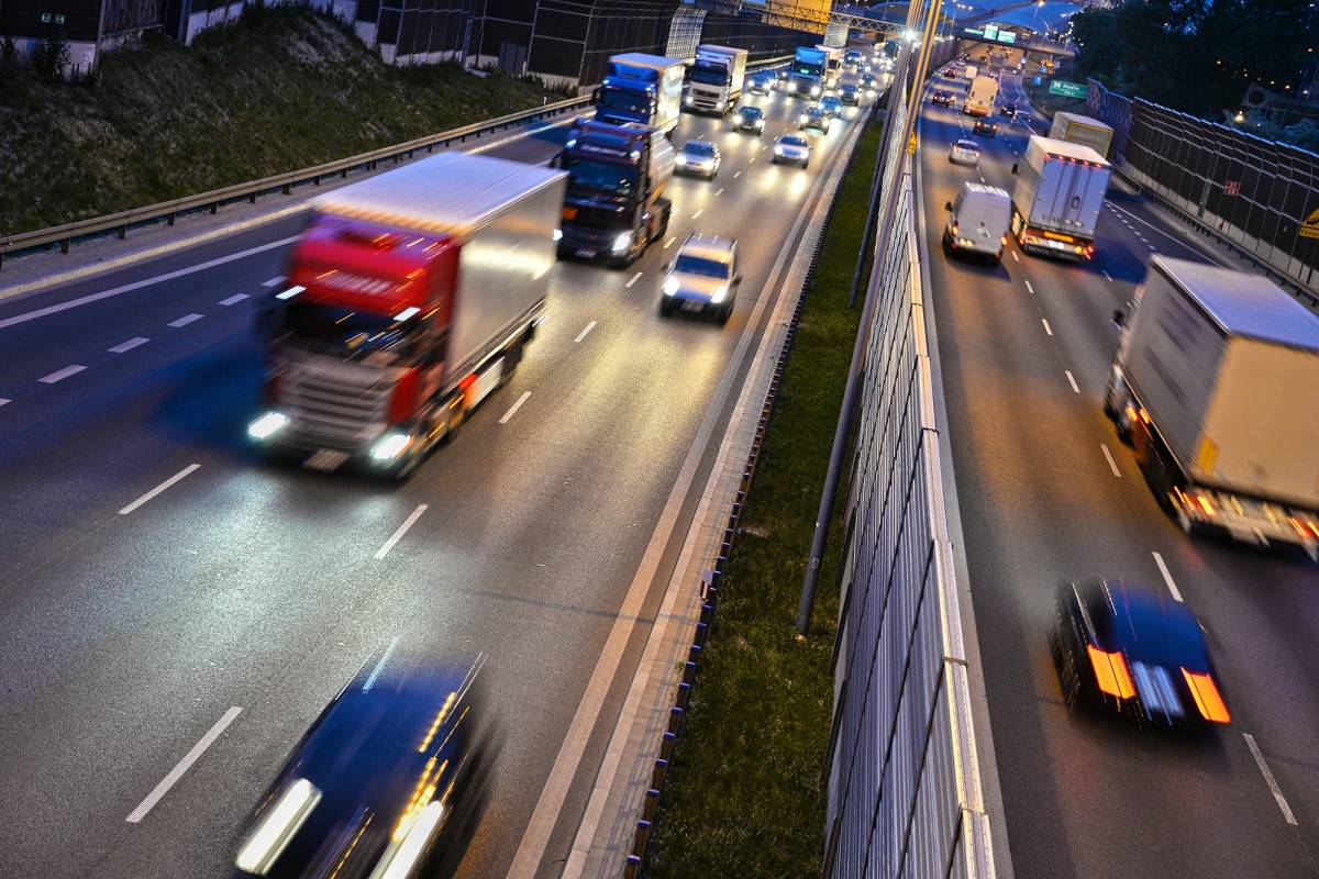 Vehicles driving on a highway with headlights on