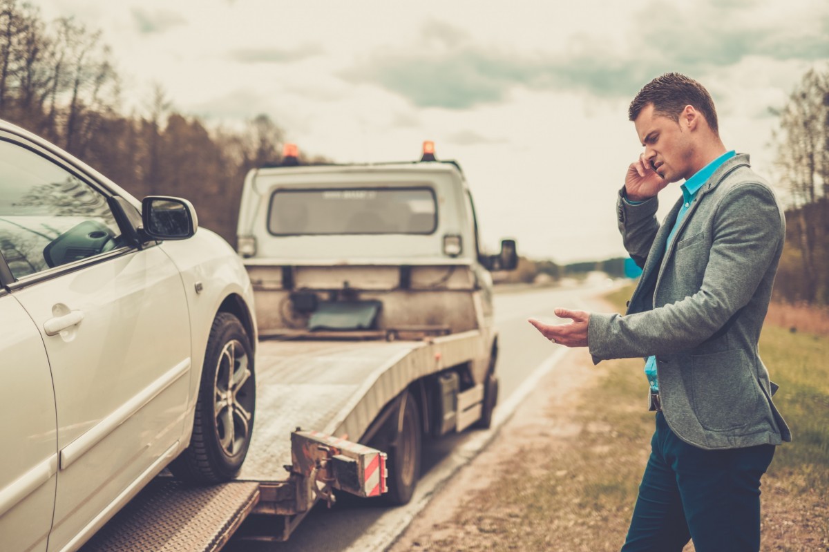 tow truck and guy calling on the phone by side of the road