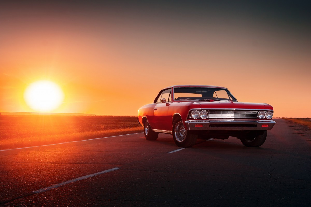 older car on road to sunset