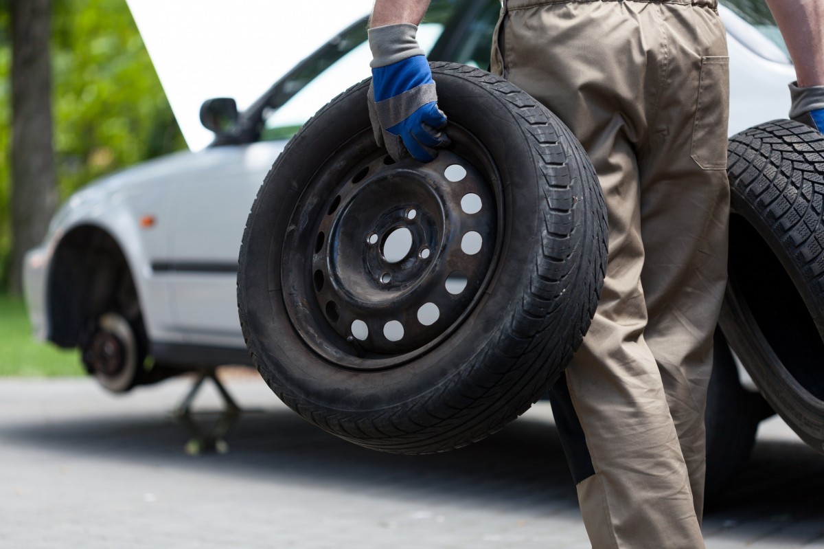 guy carrying a tire to fix it on side of the road